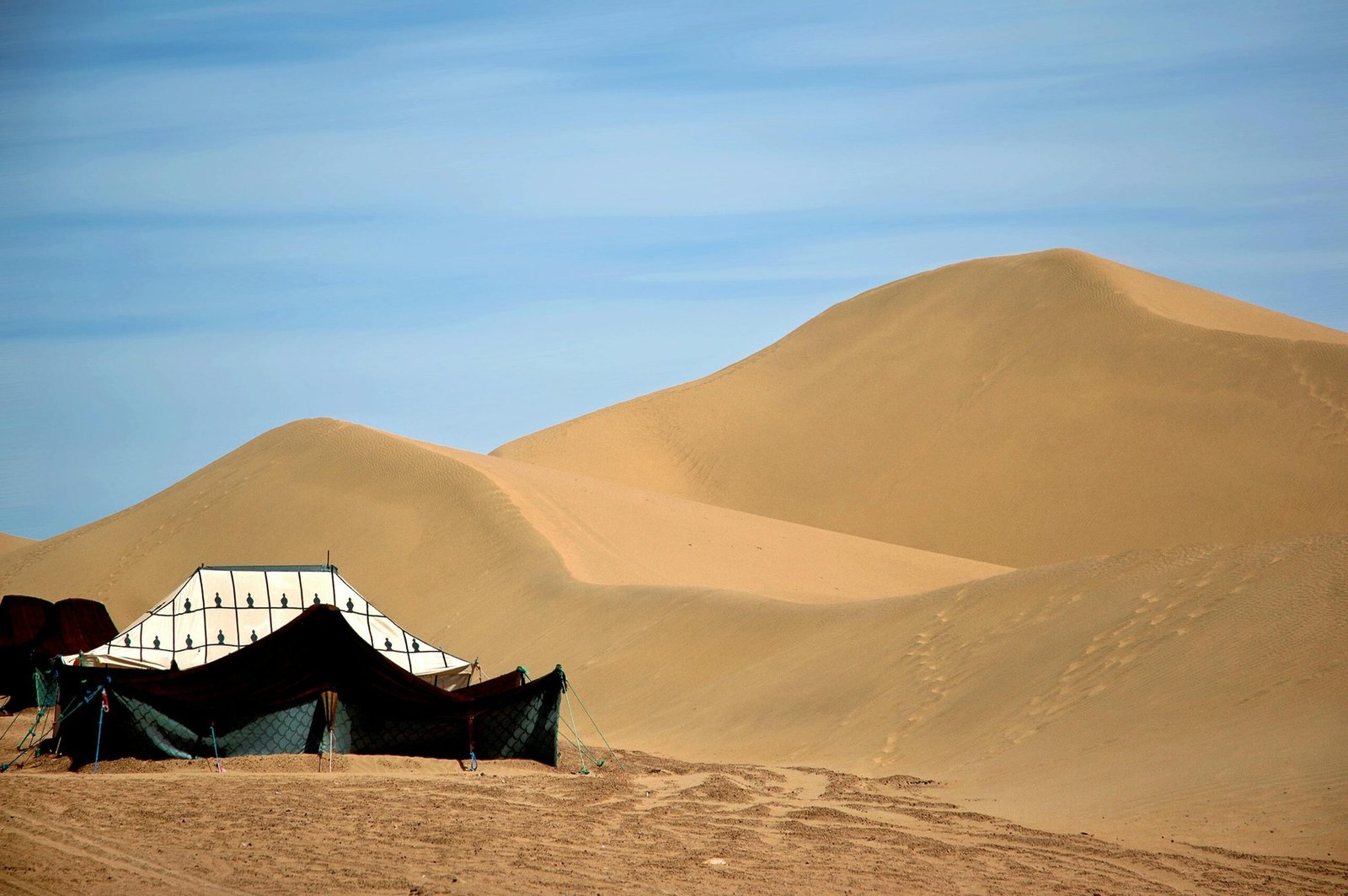 A traditional Berber tent set against the vast sand dunes of the Moroccan Sahara.